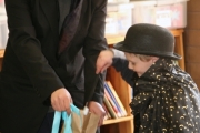 Magician Nathan Vogel shows his young apprentice how to make a ribbon appear in an empty paper bag. Photo Erin Perkins.